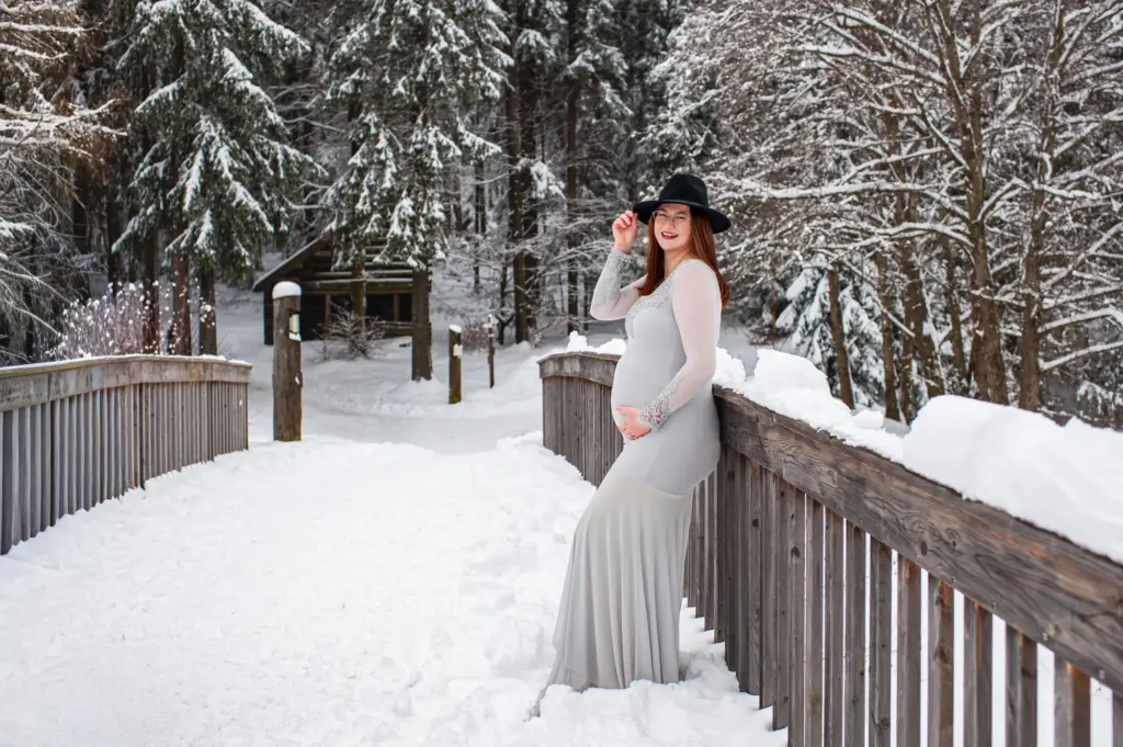Schwangere Frau mit Partner in verschneiter Winterlandschaft