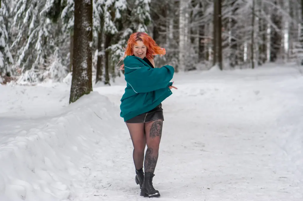 Frau tanzt und lacht im Schnee beim Selbstliebeshooting