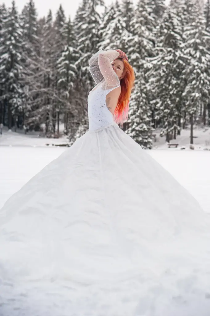 Frau im weißen Kleid mit großem Rock im Schnee